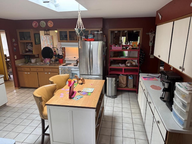 1306 Grandview Ave, Oconomowoc, WI 53066 - kitchen featuring freestanding refrigerator, white electric range oven, light tile patterned flooring, a skylight, and glass insert cabinets