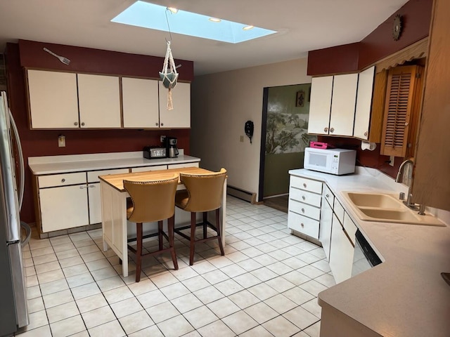 1306 Grandview Ave, Oconomowoc, WI 53066 - kitchen featuring a sink, white appliances, a skylight, baseboard heating, and light countertops