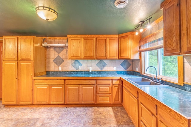 W3703 Scotch Coulee Rd, West Salem, WI 54669 - kitchen featuring a sink, brown cabinetry, backsplash, a textured ceiling, and tile counters