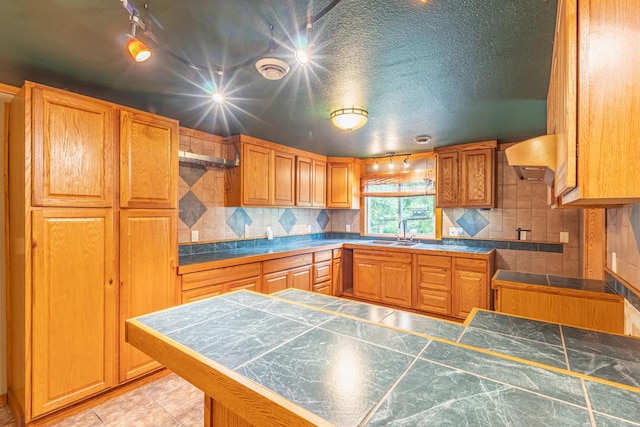 W3703 Scotch Coulee Rd, West Salem, WI 54669 - kitchen featuring a sink, decorative backsplash, wall chimney exhaust hood, brown cabinetry, and a peninsula