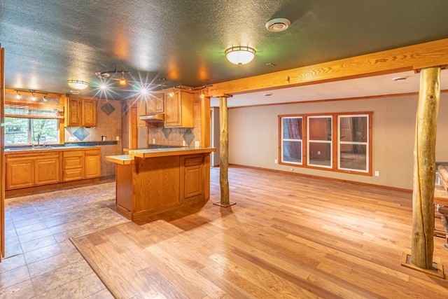 W3703 Scotch Coulee Rd, West Salem, WI 54669 - kitchen featuring ornate columns, tasteful backsplash, a kitchen breakfast bar, light countertops, and under cabinet range hood