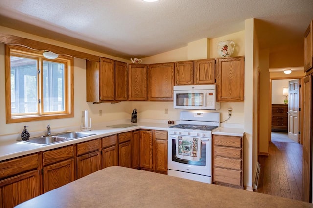 N12124 12th Ave, Necedah, WI 54646 - kitchen with white appliances, a sink, brown cabinets, vaulted ceiling, and light countertops