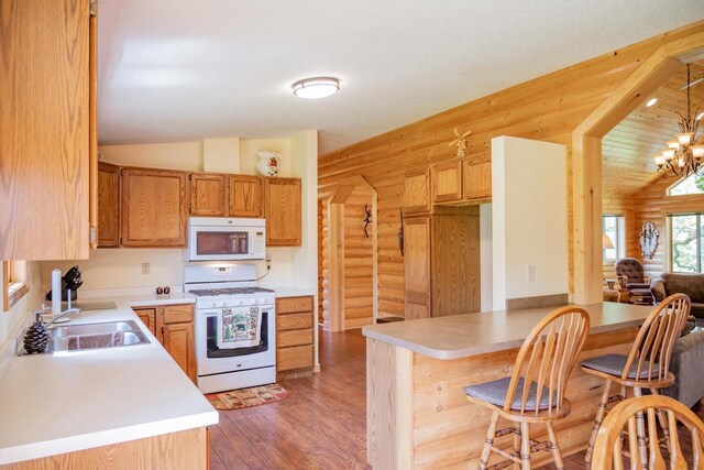 N12124 12th Ave, Necedah, WI 54646 - kitchen with white appliances, a sink, lofted ceiling, rustic walls, and a peninsula