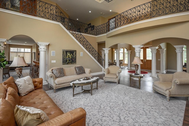 18290 Prairie Falcon Ln, Brookfield, WI 53045 - living room featuring decorative columns, arched walkways, a high ceiling, healthy amount of natural light, and wood finished floors