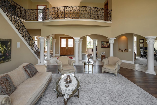 18290 Prairie Falcon Ln, Brookfield, WI 53045 - living area featuring arched walkways, decorative columns, hardwood / wood-style flooring, a towering ceiling, and baseboards
