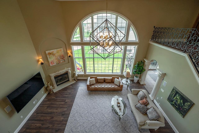 18290 Prairie Falcon Ln, Brookfield, WI 53045 - living area with a high ceiling, a fireplace with flush hearth, dark wood-style floors, baseboards, and a chandelier