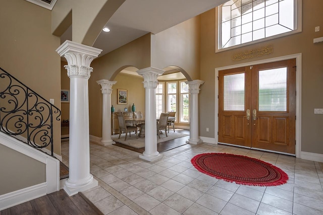 18290 Prairie Falcon Ln, Brookfield, WI 53045 - entrance foyer featuring arched walkways, a towering ceiling, baseboards, decorative columns, and light tile patterned floors