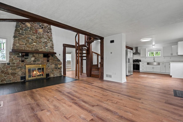 10104 Washington Ave, Mount Pleasant, WI 53177 - unfurnished living room with light wood-style flooring, a sink, a fireplace, baseboards, and a textured ceiling