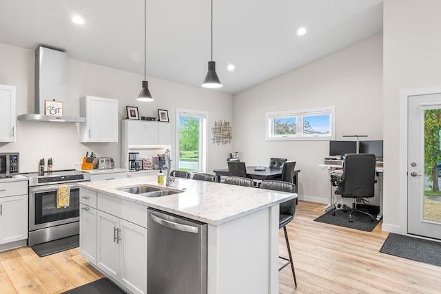 420 Sandmar Dr, Ripon, WI 54971 - kitchen featuring wall chimney exhaust hood, stainless steel appliances, a sink, a breakfast bar area, and light wood-style flooring