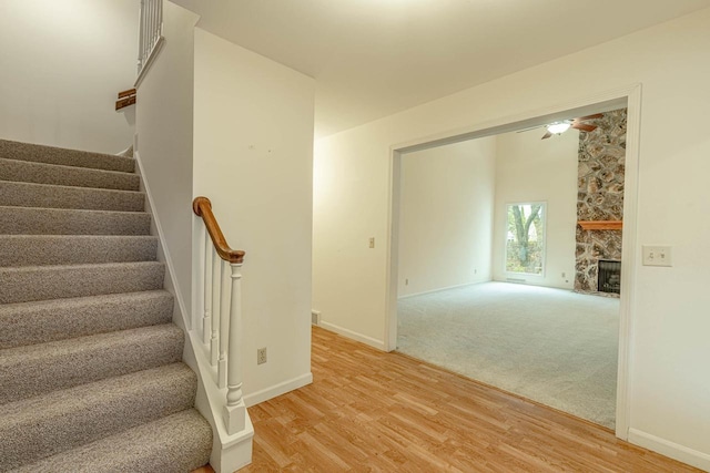 1 Winterberry Trl, Madison, WI 53717 - staircase with wood finished floors, a stone fireplace, a ceiling fan, and baseboards