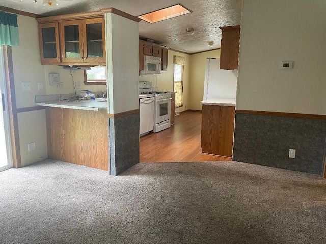 2942 Brentwood Dr, Grand Marsh, WI 53936 - kitchen featuring white appliances, carpet floors, a skylight, glass insert cabinets, and brown cabinets