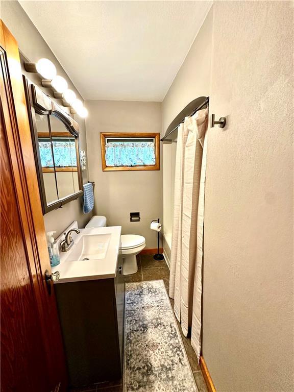1019 2nd St, Bruce, WI 54819 - full bath featuring toilet, vanity, a shower with shower curtain, tile patterned flooring, and baseboards