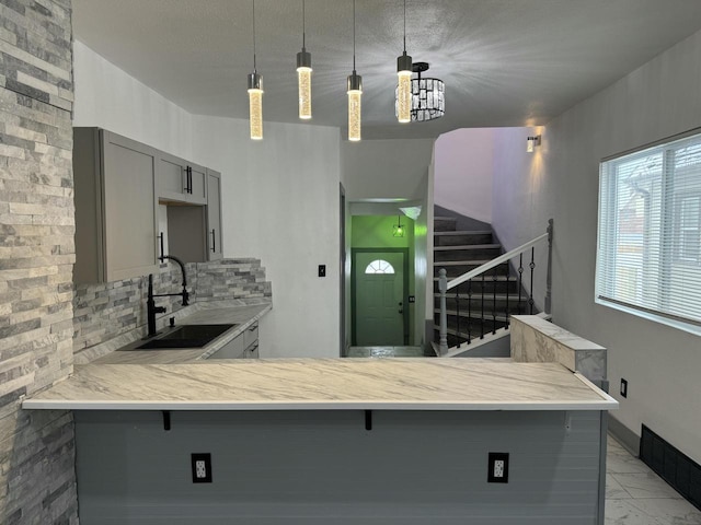 3124 N Buffum St, Milwaukee, WI 53212 - kitchen with gray cabinets, a sink, tasteful backsplash, light countertops, and light marble finish floors