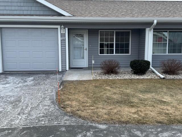 1329 S Wilson Ave, Hartford, WI 53027 - doorway to property featuring a garage, driveway, roof with shingles, and a yard