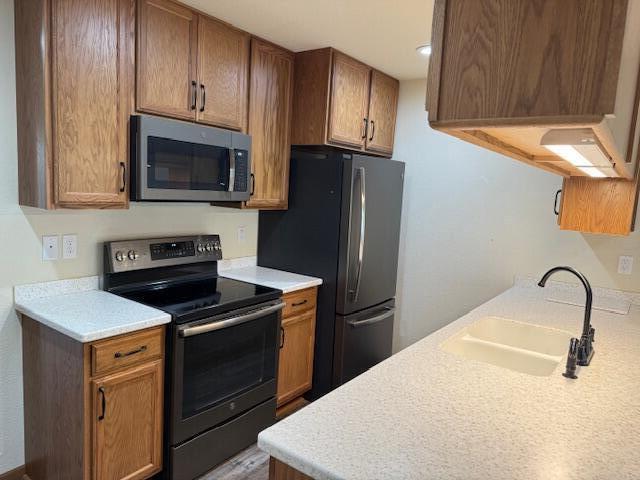 1329 S Wilson Ave, Hartford, WI 53027 - kitchen with stainless steel microwave, electric range, a sink, freestanding refrigerator, and light countertops