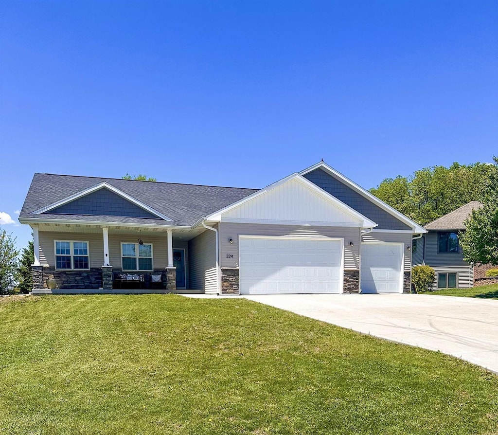 224 Clover Ln, Janesville, WI 53537 - craftsman inspired home with stone siding, a front yard, a garage, and driveway
