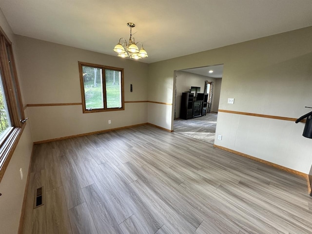 N2224 Wafle Rd, Mauston, WI 53948 - empty room featuring a chandelier, healthy amount of natural light, light wood-style flooring, and baseboards