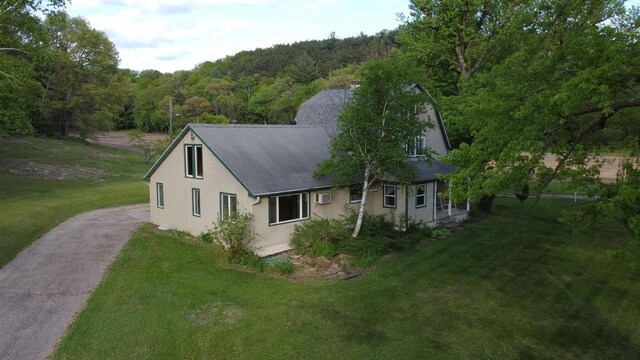 N2224 Wafle Rd, Mauston, WI 53948 - view of property exterior featuring driveway, a wooded view, a yard, and roof with shingles