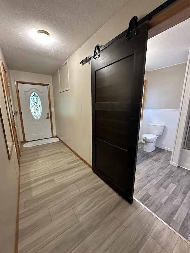 N2224 Wafle Rd, Mauston, WI 53948 - corridor featuring a barn door, a textured ceiling, light wood-type flooring, and baseboards
