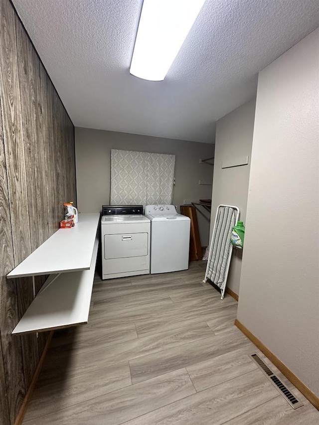 N2224 Wafle Rd, Mauston, WI 53948 - laundry room with washing machine and dryer, a textured ceiling, baseboards, and wooden walls