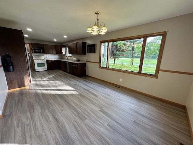 N2224 Wafle Rd, Mauston, WI 53948 - kitchen featuring white gas stove, black microwave, baseboards, light countertops, and a chandelier