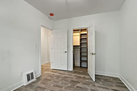 1107 Perry Ave, Racine, WI 53406 - unfurnished bedroom with baseboards, wood finished floors, a closet, and a spacious closet