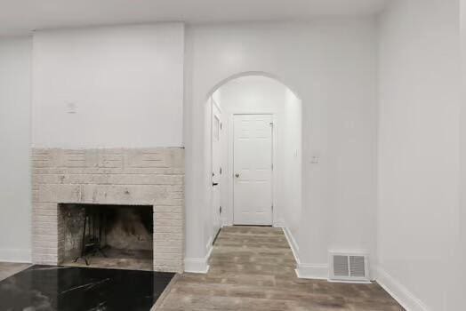 1107 Perry Ave, Racine, WI 53406 - living area featuring arched walkways, wood finished floors, a brick fireplace, and baseboards