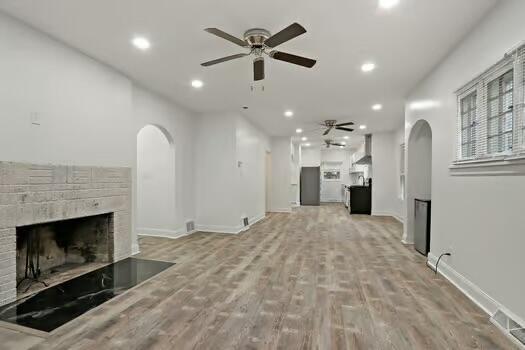 1107 Perry Ave, Racine, WI 53406 - unfurnished living room featuring arched walkways, ceiling fan, a fireplace, light wood-type flooring, and recessed lighting