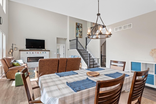 160 Candleberry Ln, Grafton, WI 53024 - dining area with wood finished floors, a chandelier, a towering ceiling, stairway, and a glass covered fireplace