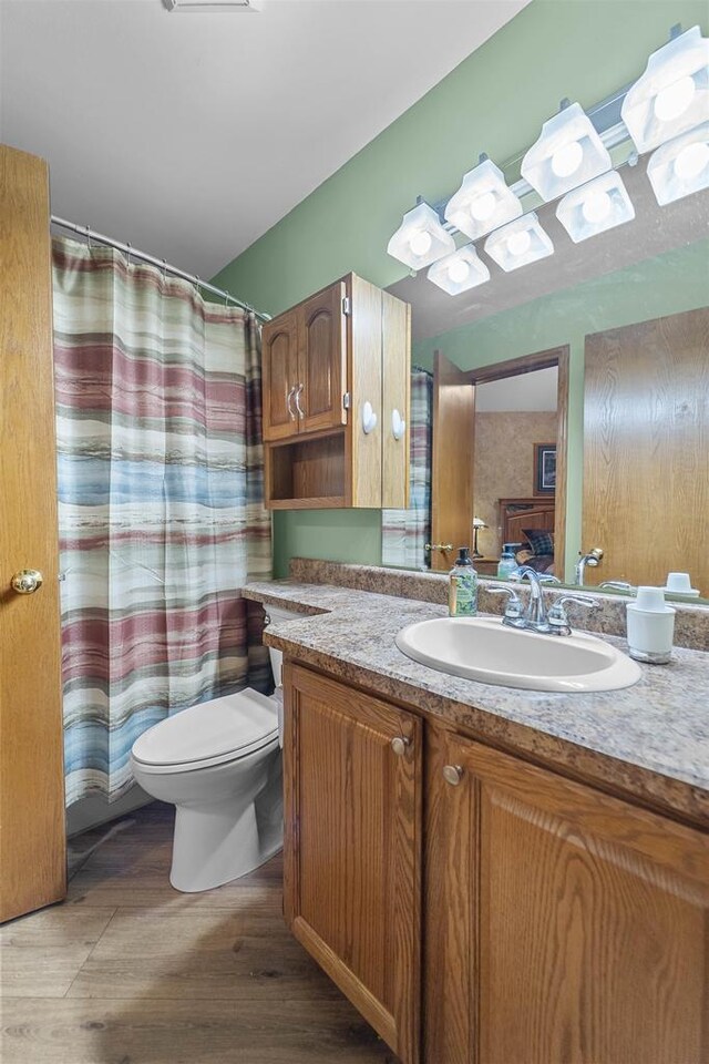 W5204 N Osprey Dr, New Lisbon, WI 53950 - bathroom with toilet, vanity, wood finished floors, and curtained shower