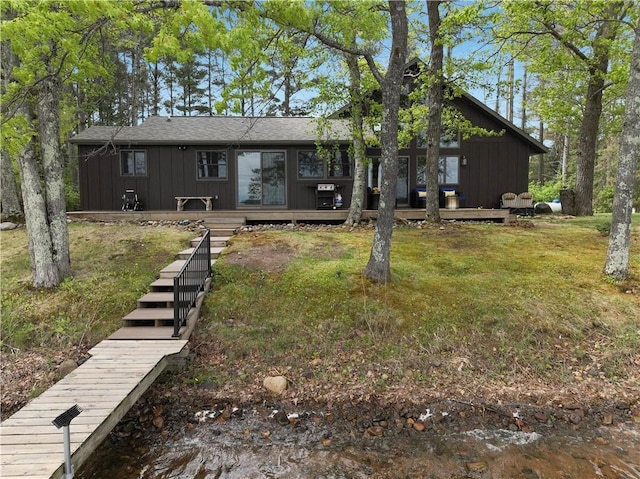 14856W Valhalla Dr, Hayward, WI 54843 - view of front facade featuring board and batten siding, a wooden deck, a front yard, and a shingled roof