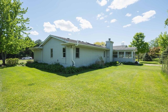W5670 School Rd, Walworth, WI 53184 - rear view of house featuring a yard, a chimney, and a sunroom