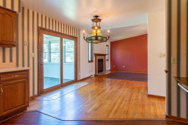 W5670 School Rd, Walworth, WI 53184 - unfurnished dining area featuring light wood-type flooring, baseboards, wallpapered walls, a chandelier, and a fireplace
