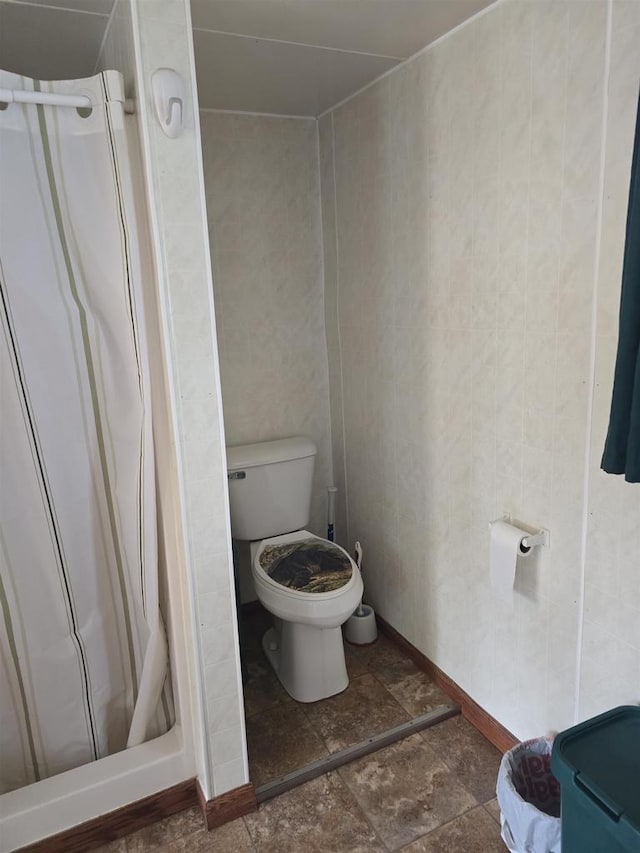 Pine Ln, Bloomington, WI 53804 - bathroom featuring a stall shower, baseboards, toilet, and stone finish floors