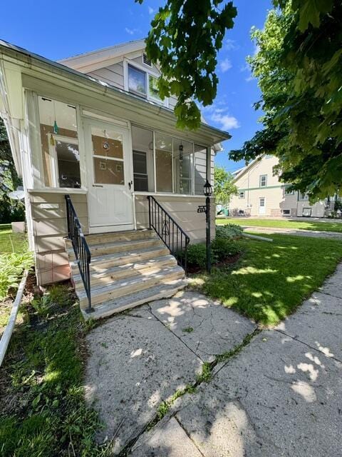 219 E 9th St, Fond Du Lac, WI 54935 - view of front of home featuring entry steps, a sunroom, and a front lawn