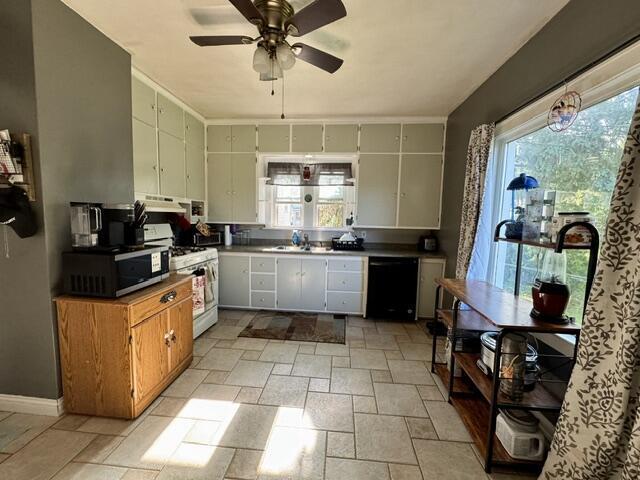219 E 9th St, Fond Du Lac, WI 54935 - kitchen featuring black dishwasher, white range with gas stovetop, stone tile flooring, a ceiling fan, and dark countertops