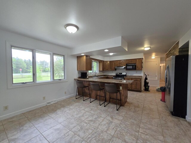 4211 State Highway 173, Nekoosa, WI 54457 - kitchen featuring appliances with stainless steel finishes, a peninsula, a sink, under cabinet range hood, and baseboards