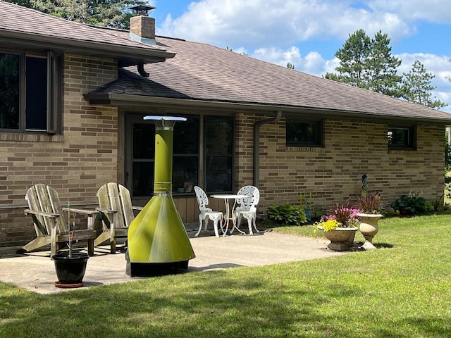 4211 State Highway 173, Nekoosa, WI 54457 - rear view of house featuring a shingled roof, brick siding, a patio area, and a yard