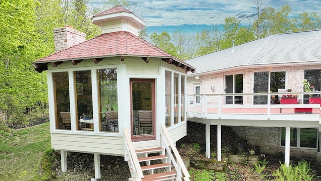 W11078 S Shore Rd, Deerbrook, WI 54425 - back of house with a deck, a chimney, a shingled roof, and a sunroom