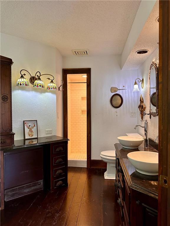 16680W Raining Tree Rd, Stone Lake, WI 54876 - bathroom with a textured ceiling, double vanity, wood-type flooring, baseboards, and toilet