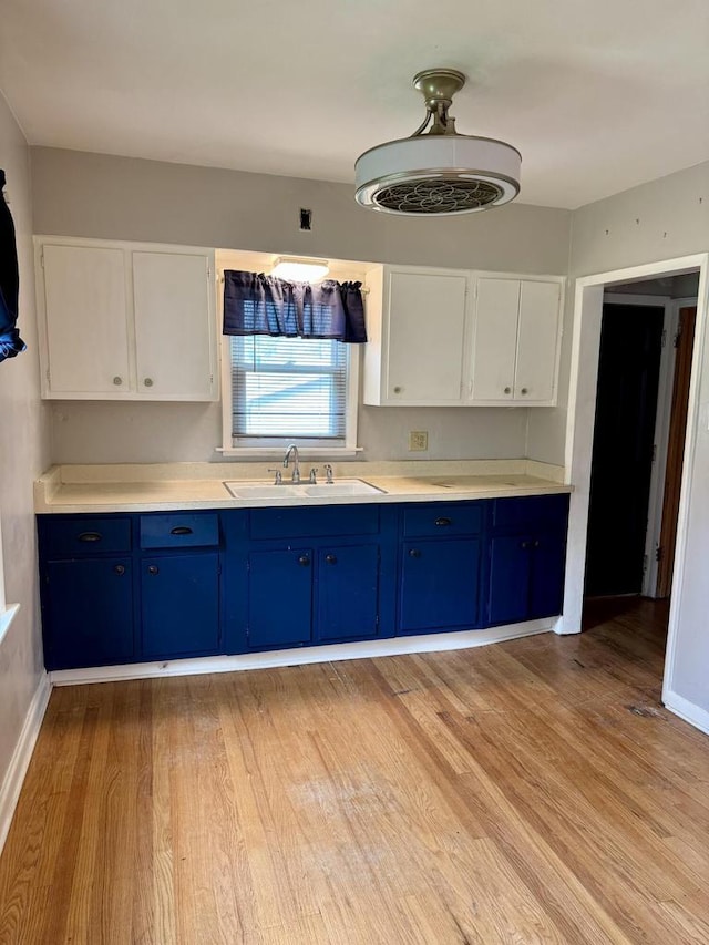 4717 N 19th St, Milwaukee, WI 53209 - kitchen featuring blue cabinets, a sink, light wood-type flooring, and white cabinetry