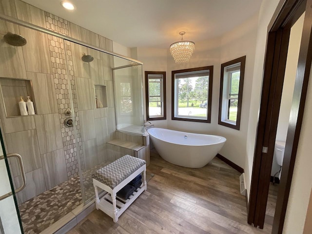 W10559 Hickory Point Rd, Beaver Dam, WI 53916 - bathroom with a freestanding tub, a stall shower, wood finished floors, a chandelier, and baseboards