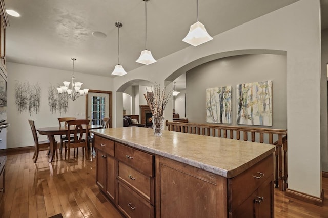 6383 Northwestern Dr, Rhinelander, WI 54501 - kitchen featuring arched walkways, a center island, dark wood finished floors, a chandelier, and light countertops