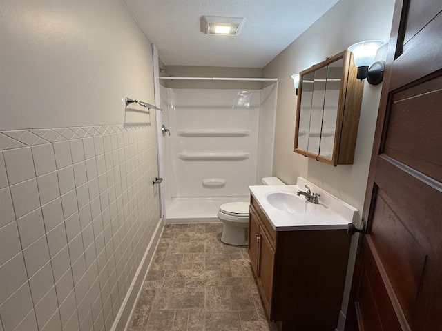 3400 Vine St, Stevens Point, WI 54481 - bathroom with tile walls, vanity, toilet, a shower, and stone finish flooring