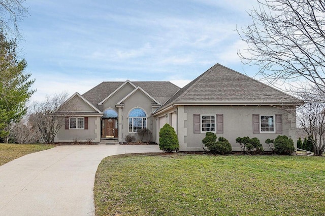217 Steeple Ct, Johnson Creek, WI 53038 - view of front of house featuring concrete driveway, stucco siding, a front yard, and roof with shingles