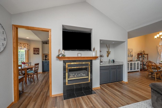 217 Steeple Ct, Johnson Creek, WI 53038 - living room with a tiled fireplace, wood finished floors, a chandelier, baseboards, and high vaulted ceiling