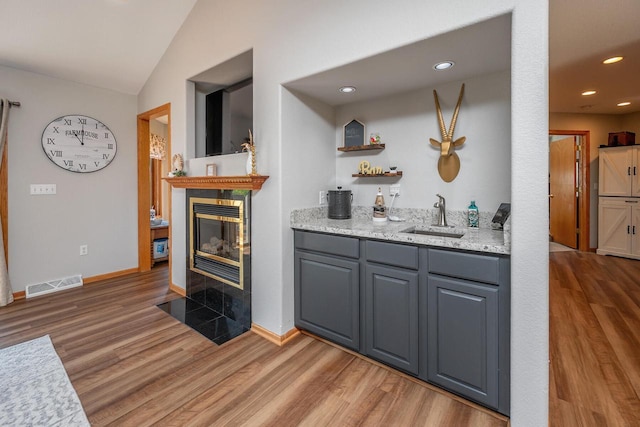 217 Steeple Ct, Johnson Creek, WI 53038 - bar featuring a sink, light wood finished floors, a tiled fireplace, vaulted ceiling, and recessed lighting