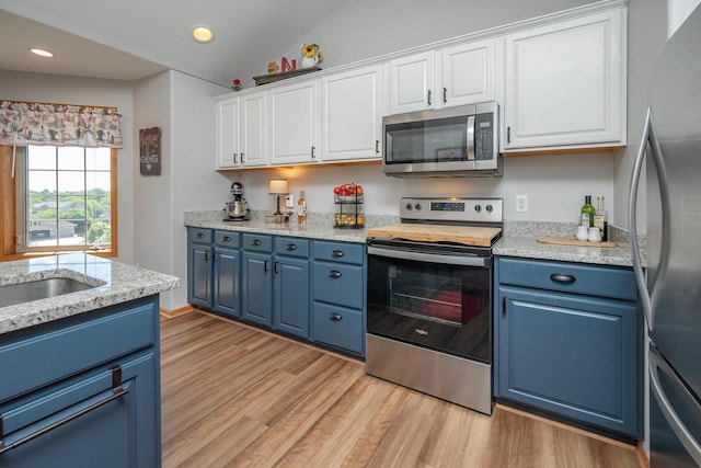217 Steeple Ct, Johnson Creek, WI 53038 - kitchen featuring appliances with stainless steel finishes, blue cabinets, white cabinets, light wood-type flooring, and vaulted ceiling