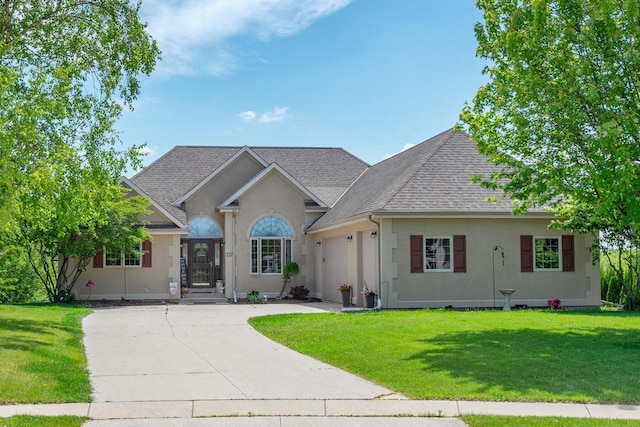 217 Steeple Ct, Johnson Creek, WI 53038 - single story home featuring roof with shingles, an attached garage, stucco siding, concrete driveway, and a front yard