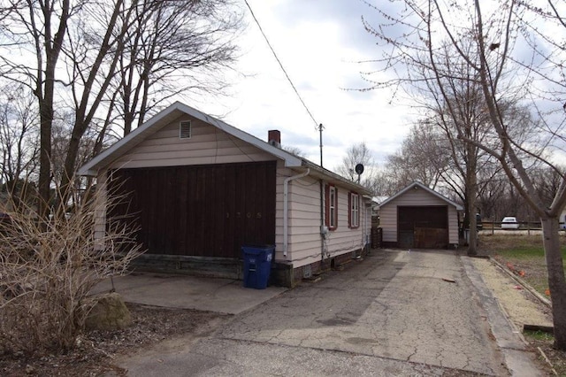 1305 La Crescent St, La Crosse, WI 54603 - view of side of home featuring driveway, a detached garage, an outbuilding, and a chimney